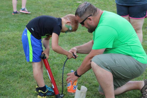 Counselor helping camper fill up a water rocket